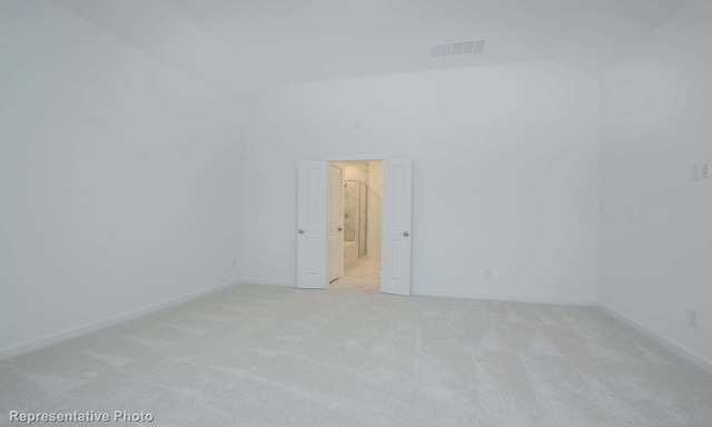 unfurnished room with lofted ceiling and light colored carpet