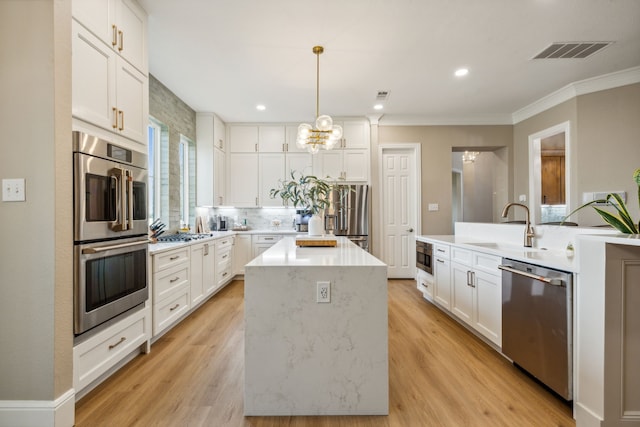 kitchen featuring white cabinetry, light hardwood / wood-style flooring, appliances with stainless steel finishes, and decorative light fixtures