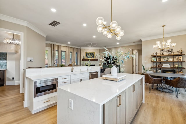 kitchen with white cabinetry, light hardwood / wood-style flooring, a kitchen island, and hanging light fixtures