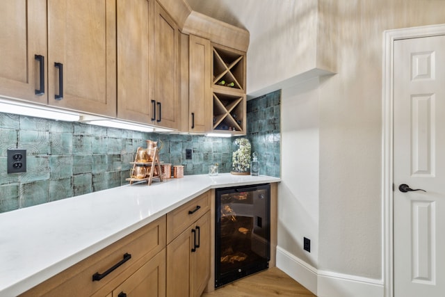 bar with wine cooler, tasteful backsplash, light brown cabinetry, and light wood-type flooring