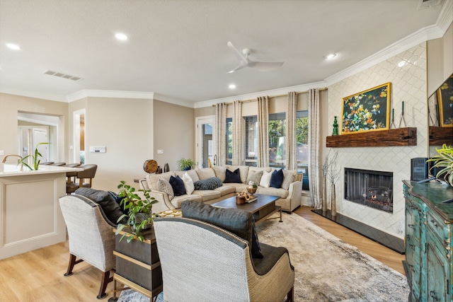 living room with light hardwood / wood-style floors, crown molding, and ceiling fan