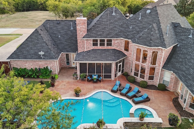 view of pool with a patio area, an in ground hot tub, and a sunroom