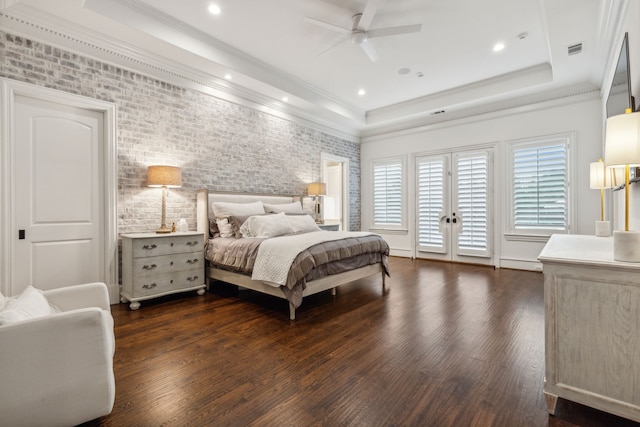 bedroom with ceiling fan, a tray ceiling, dark hardwood / wood-style flooring, and access to exterior