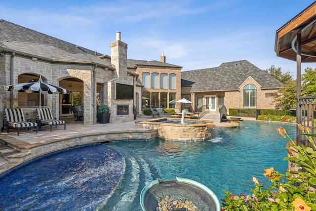 view of pool with a patio area, pool water feature, and an in ground hot tub