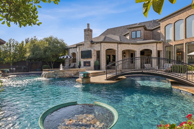 view of swimming pool featuring pool water feature and an in ground hot tub