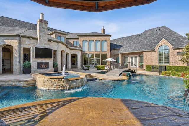 view of pool with a patio, pool water feature, and an in ground hot tub