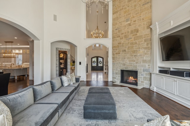 living room with a towering ceiling, sink, a fireplace, and dark hardwood / wood-style flooring