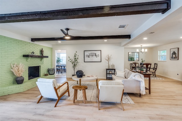 living room featuring ceiling fan with notable chandelier, beam ceiling, light hardwood / wood-style flooring, and a fireplace