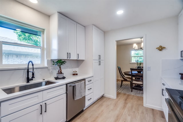 kitchen featuring sink, backsplash, stainless steel dishwasher, white cabinets, and light hardwood / wood-style flooring