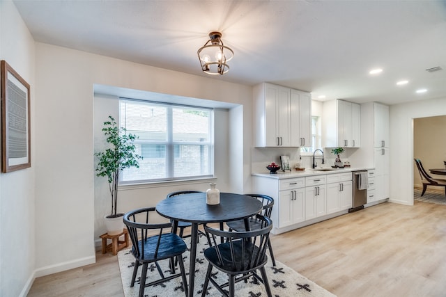 dining room featuring an inviting chandelier, sink, and light wood-type flooring