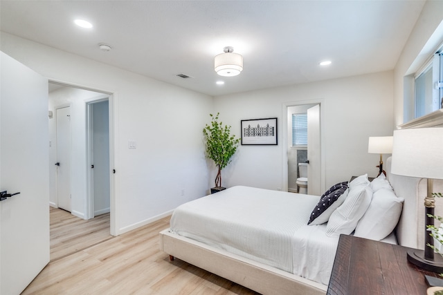 bedroom featuring connected bathroom and light hardwood / wood-style floors