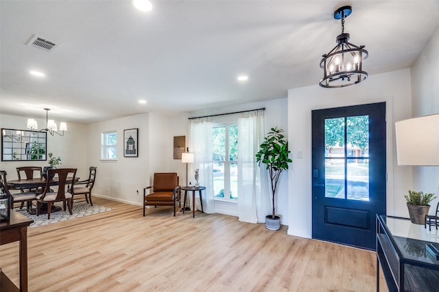 foyer featuring a notable chandelier, a wealth of natural light, and light wood-type flooring