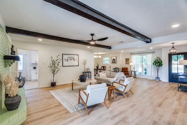 living room with light hardwood / wood-style floors, beam ceiling, and ceiling fan with notable chandelier