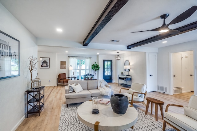 living room with beam ceiling, an inviting chandelier, and light wood-type flooring