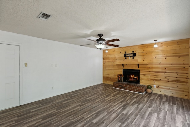 unfurnished living room with a textured ceiling, dark hardwood / wood-style flooring, and wooden walls