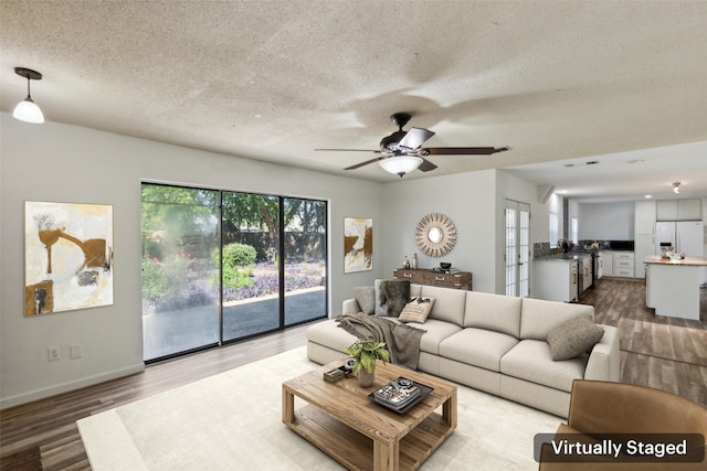 living room with ceiling fan, plenty of natural light, hardwood / wood-style floors, and a textured ceiling