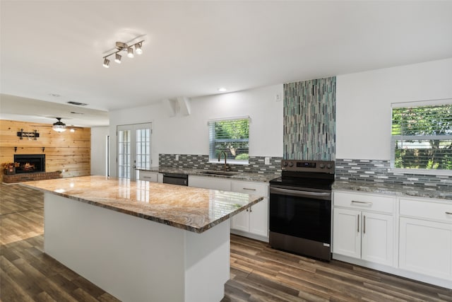 kitchen featuring stainless steel electric stove, decorative backsplash, white cabinetry, and sink