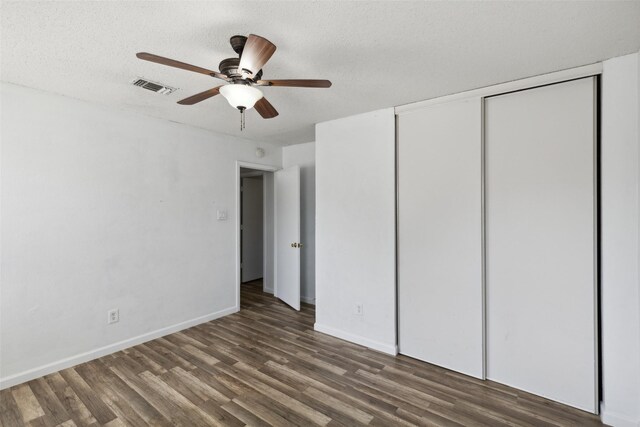 empty room featuring a textured ceiling, ceiling fan, and dark wood-type flooring