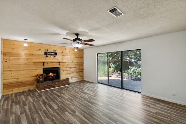 unfurnished living room featuring wooden walls, dark wood-type flooring, and a textured ceiling