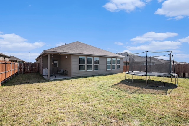 back of house featuring a yard, a patio, and a trampoline