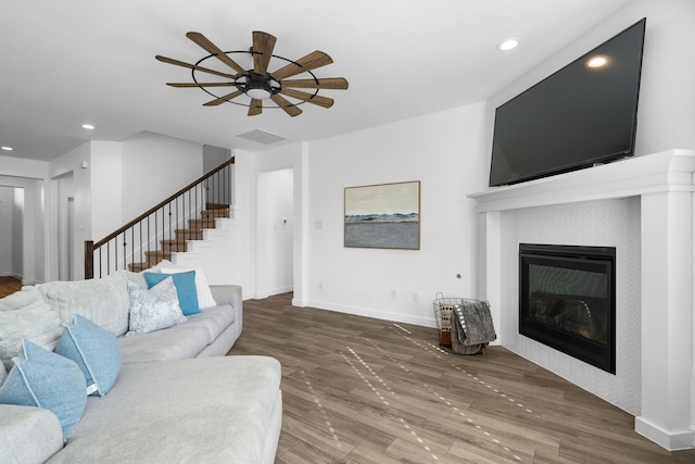 living room with hardwood / wood-style flooring, a tile fireplace, and ceiling fan