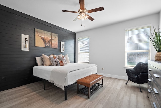 bedroom with light hardwood / wood-style floors, wood walls, and ceiling fan