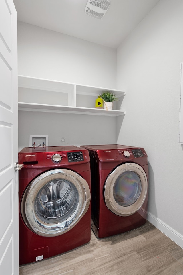 clothes washing area featuring independent washer and dryer and light wood-type flooring