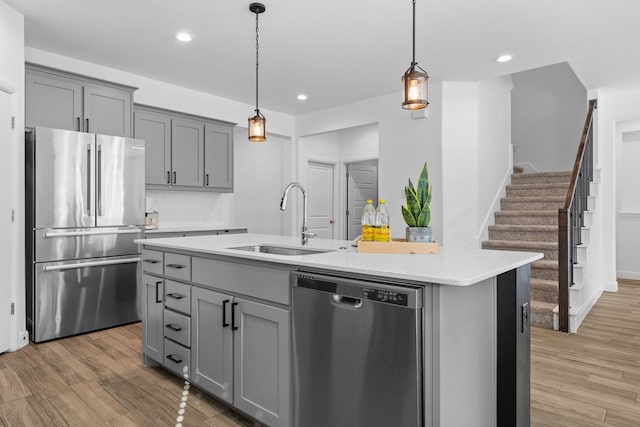 kitchen featuring light hardwood / wood-style flooring, stainless steel appliances, sink, and an island with sink