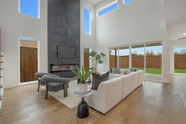 living room with a premium fireplace, a high ceiling, and light hardwood / wood-style floors