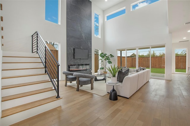 living room with a large fireplace, a high ceiling, and light wood-type flooring