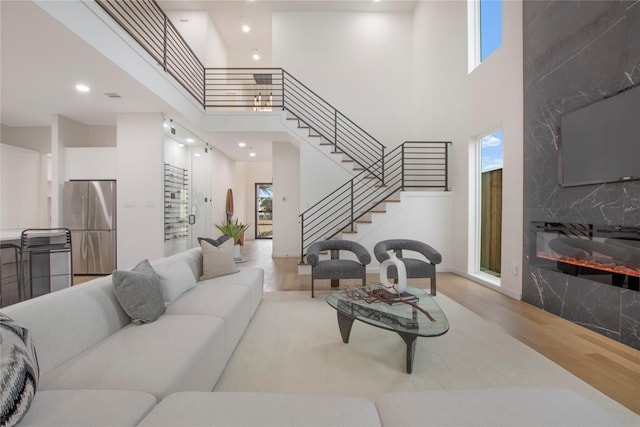 living room with light hardwood / wood-style floors, a high end fireplace, and a high ceiling