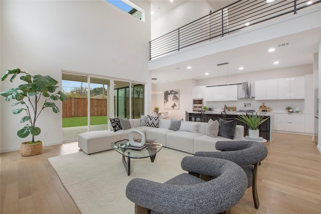 living room with light hardwood / wood-style floors, a towering ceiling, and sink