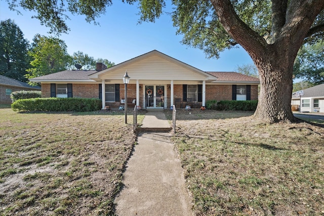 ranch-style house featuring covered porch and a front lawn