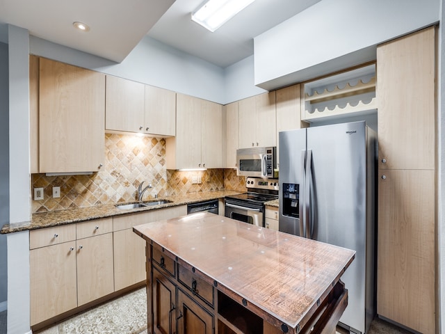 kitchen featuring light stone countertops, sink, a center island, stainless steel appliances, and decorative backsplash