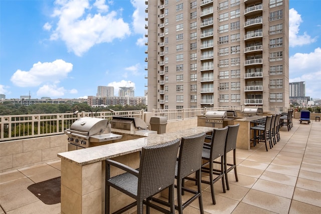 view of patio / terrace featuring a balcony, exterior kitchen, grilling area, and an outdoor bar