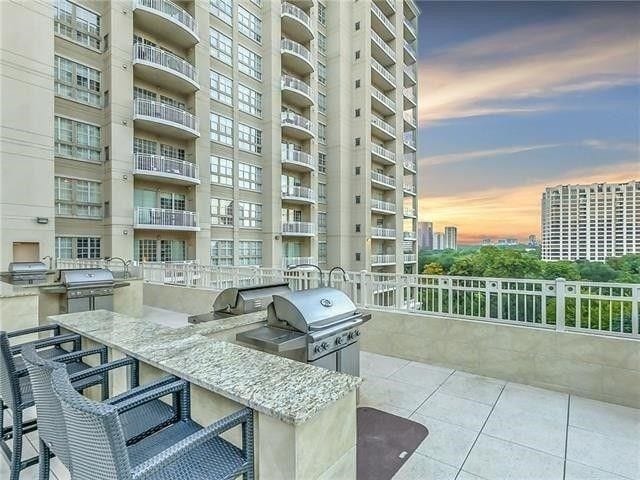 patio terrace at dusk featuring area for grilling, a balcony, and an outdoor kitchen