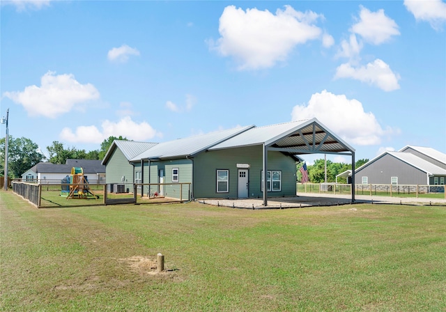 rear view of property with a yard and a playground