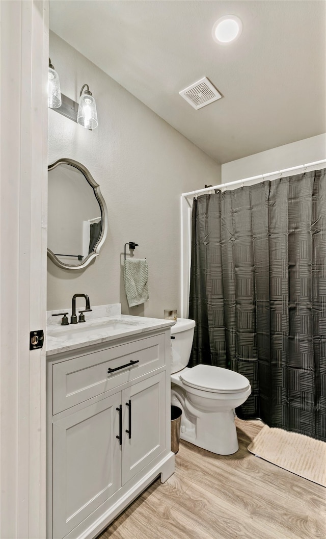 bathroom with vanity, hardwood / wood-style flooring, toilet, and walk in shower