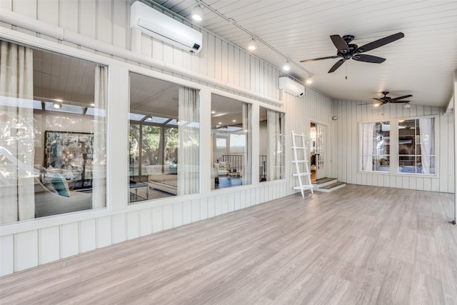 unfurnished sunroom with a wall unit AC, ceiling fan, rail lighting, and vaulted ceiling