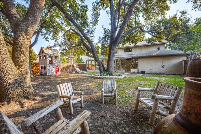 15211 Meandering Way, Dallas, TX 75248 - view of yard featuring a sunroom, a fenced backyard, and a playground