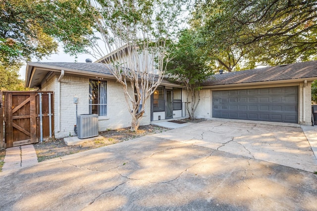 15211 Meandering Way, Dallas, TX 75248 - view of front facade featuring roof with shingles, brick siding, a garage, central AC unit, and concrete driveway