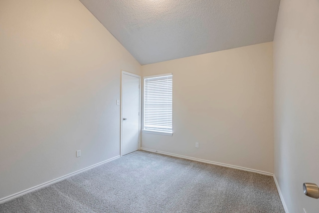 spare room featuring a textured ceiling, carpet flooring, and lofted ceiling