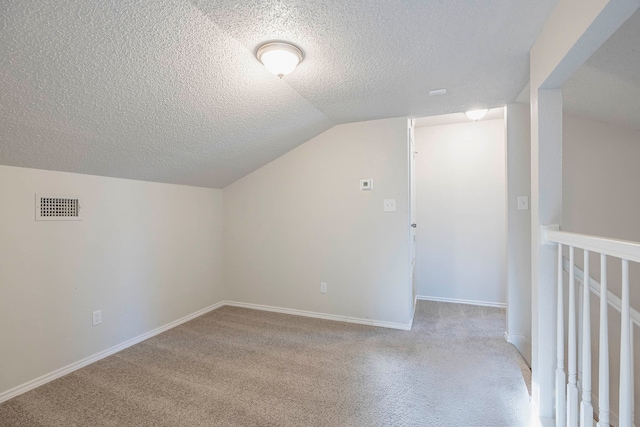 bonus room featuring a textured ceiling, vaulted ceiling, and light colored carpet