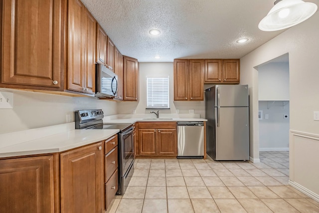 kitchen with light tile patterned floors, stainless steel appliances, a textured ceiling, and sink