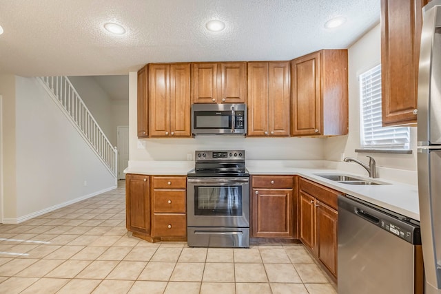 kitchen featuring light tile patterned floors, stainless steel appliances, a textured ceiling, and sink