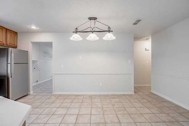 kitchen with stainless steel fridge, a textured ceiling, light tile patterned floors, and pendant lighting