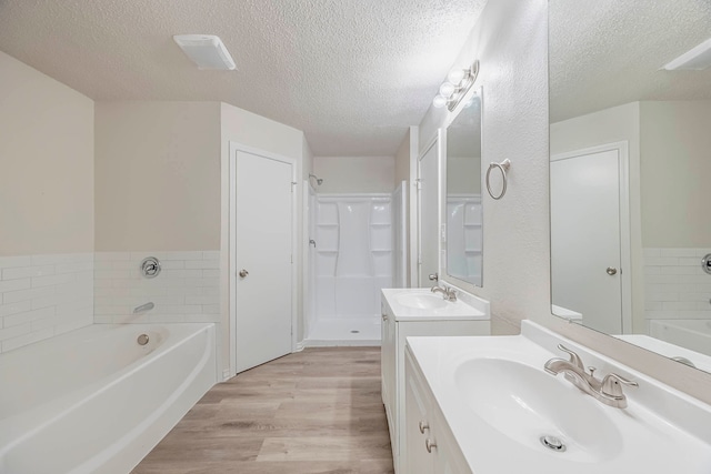 bathroom with vanity, plus walk in shower, a textured ceiling, and hardwood / wood-style floors