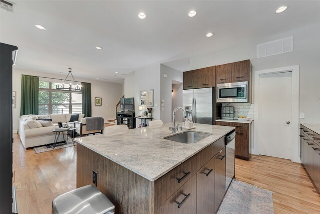 kitchen featuring sink, an island with sink, light hardwood / wood-style flooring, and stainless steel appliances