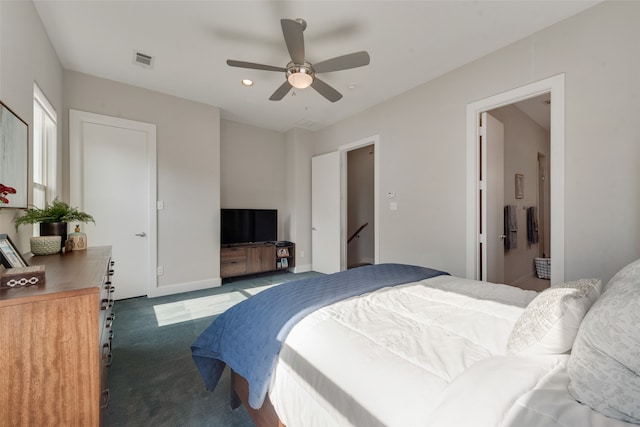 bedroom with ensuite bathroom, dark carpet, and ceiling fan