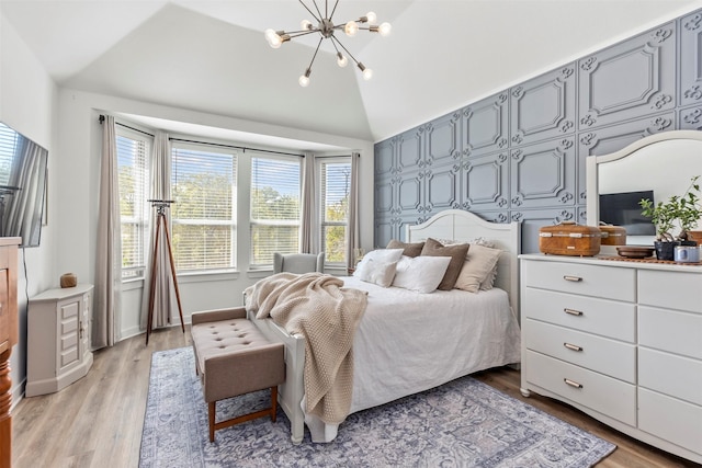 bedroom featuring a chandelier, light wood-type flooring, and lofted ceiling